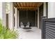 A shaded porch with a swing and two chairs offers a cozy outdoor seating area at 1878 Headquarters Plantation Dr, Johns Island, SC 29455