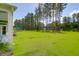 Spacious green backyard featuring tall trees and lush grass with a glimpse of a blue outdoor canopy at 217 Quimby Hill Dr, Huger, SC 29450