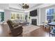 Bright living room with hardwood floors, tray ceilings, a fireplace, and large windows overlooking the yard at 217 Quimby Hill Dr, Huger, SC 29450