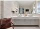 Bathroom featuring double sinks, a large mirror, white cabinets and marble tile at 32 Prioleau St # J, Charleston, SC 29401