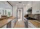 Galley kitchen with stainless steel appliances, stone countertops, tile backsplash, and lots of natural light at 32 Prioleau St # J, Charleston, SC 29401