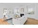 Elegant living room with a fireplace, large windows, hardwood floors, and white sofas with blue accents at 325 Blowing Fresh Dr, Charleston, SC 29492