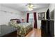 Cozy bedroom with a floral-patterned bed, red accents, wooden floors, and a TV for relaxed, comfortable living at 3347 Walter Drive, Johns Island, SC 29455