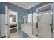Bright bathroom featuring a soaking tub and glass-enclosed shower with a blue accent wall and an open door to the bedroom at 5011 W Liberty Meadows Dr, Summerville, SC 29485