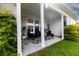 Covered patio features a seating area with neutral furniture, lush landscaping, and a green and white leaf patterned rug at 558 Pendleton Dr, Moncks Corner, SC 29461