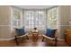 Cozy sitting area with bay windows, two chairs, wood floors, and a small table at 9091 Delancey Cir, North Charleston, SC 29406