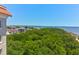 High angle scenic cityscape shot showcasing rooftops, lush trees, and coastal ocean views against a clear blue sky at 1 King # 702, Charleston, SC 29401