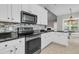 Bright kitchen features black appliances, white cabinets, black countertops and stone tile backsplash at 114 Marshside Dr, Summerville, SC 29485