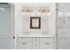 Bathroom with double sink vanity, decorative mirror, brass lighting, and a large walk in shower with marble tiling at 1989 Nitsa St, Johns Island, SC 29455