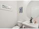 Powder room with white pedestal sink, toilet, oval mirror, and framed artwork at 1989 Nitsa St, Johns Island, SC 29455