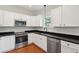 Modern kitchen with white cabinets, stainless steel appliances, sleek black countertops, and wood flooring at 1989 Nitsa St, Johns Island, SC 29455