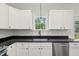 Modern kitchen features sleek black counters, stainless steel dishwasher, and bright white cabinets at 1989 Nitsa St, Johns Island, SC 29455