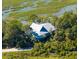 Aerial shot of the home showcasing its setting amongst trees with views of the marsh at 226 Old House Ln, Dewees Island, SC 29451