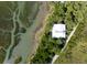 Aerial perspective of a home near the coast, nestled amidst a scenic landscape of water and trees at 226 Old House Ln, Dewees Island, SC 29451