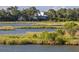 Picturesque marsh view with modern white home nestled among the trees in the background at 226 Old House Ln, Dewees Island, SC 29451