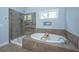 Bathroom featuring a soaking tub, glass-enclosed shower, neutral tiling and a bright window at 2997 Sturbridge Rd, Mount Pleasant, SC 29466