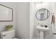Stylish half-bathroom with a pedestal sink, round mirror, and modern fixtures set against a neutral wall at 3082 Emma Ln, Mount Pleasant, SC 29466