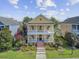 Charming yellow home boasting a double porch, landscaped front yard, and inviting curb appeal on a sunny day at 312 Germander Ave, Summerville, SC 29483