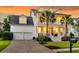 Charming two-story home with a welcoming porch, palm trees, and a two-car garage, all bathed in warm evening light at 3224 Hatchway Dr, Mount Pleasant, SC 29466