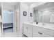 Well-lit bathroom featuring a double vanity, large mirror, white cabinets, and a glimpse into the bedroom, offering convenience at 352 Matuskovic Dr, Charleston, SC 29414
