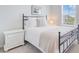 Bright bedroom featuring a sleek black metal bed frame, white bedding, and a view from the window at 352 Matuskovic Dr, Charleston, SC 29414
