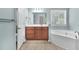 Light-filled bathroom with wood vanity, a large mirror, and soaking tub at 354 Beachgrass Ln, Summerville, SC 29486