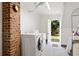 Bright laundry room with white appliances, brick accent wall, and a view to the outdoor landscape at 4626 O'Hear Ave, North Charleston, SC 29405