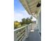This balcony has white wood railings and a gray deck with a view of tropical foliage and blue skies at 55 Seagrass Ln, Isle of Palms, SC 29451