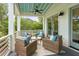 Inviting covered porch features comfortable seating, a ceiling fan, and white railings with wooded views at 55 Seagrass Ln, Isle of Palms, SC 29451