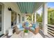 Relaxing covered porch boasts cozy seating, a ceiling fan, and white railings with beautiful wooded views at 55 Seagrass Ln, Isle of Palms, SC 29451