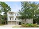 Charming three-story home with a two-car garage, well-kept lawn, and mature trees enhancing curb appeal at 55 Seagrass Ln, Isle of Palms, SC 29451