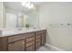 Bathroom with double sinks, wood cabinets, and light green walls at 7045 Stonecrop Ln, Johns Island, SC 29455