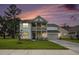 Beautiful home with a double porch, lush green lawn, and the colorful hues of the sunsetting sky at 7045 Stonecrop Ln, Johns Island, SC 29455
