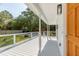 Expansive front porch showcasing white railings, elegant columns, and scenic views of the landscaped front yard at 7986 Highway 162, Hollywood, SC 29449
