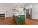 Modern kitchen boasts a large green island, white cabinets, stainless steel appliances, and a cozy fireplace nearby at 7986 Highway 162, Hollywood, SC 29449