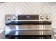Close-up of a stainless steel electric range with digital controls and a white tile backsplash at 7986 Highway 162, Hollywood, SC 29449