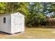 White storage shed with roof overhang and a window in a green, tree-lined yard at 7986 Highway 162, Hollywood, SC 29449