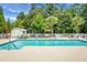 Community pool with clear blue water, surrounded by lounge chairs, lush greenery, and a play area at 8800 Dorchester Rd # 2004, North Charleston, SC 29420