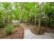 A backyard with a stepping stone path surrounded by trees and a white wooden fence at 114 Grand Palm Ln, Summerville, SC 29485