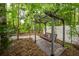 Tranquil outdoor seating area with a wooden swing, set amidst lush greenery and tall trees at 114 Grand Palm Ln, Summerville, SC 29485