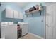 Functional laundry room with white washer and dryer, overhead cabinets, and blue wall accents at 135 Gaslight Blvd, Summerville, SC 29483