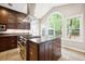 Bright kitchen featuring a large island with cooktop, stainless steel range hood and a large arched window at 138 Shadowmoss Pkwy, Charleston, SC 29414