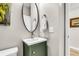 Charming powder room with an oval mirror, green vanity and modern fixtures at 2226 Arthur Rose Ln, Johns Island, SC 29455
