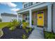Inviting covered front porch with a bright yellow door, decorative fountain, and lush landscaping at 225 N Light Way, Summerville, SC 29486