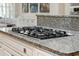 Close-up of modern kitchen with granite countertop and integrated gas cooktop, and white cabinets at 2645 Gnarled Pine, Seabrook Island, SC 29455