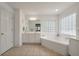 Well-lit bathroom featuring tile flooring, a tub with tile surround and a glass block window at 3038 Penny Ln, Johns Island, SC 29455