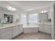 Bright bathroom featuring dual sinks, tile floors and a soaking tub with glass block window at 3038 Penny Ln, Johns Island, SC 29455