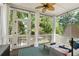 A screened porch with a ceiling fan, white curtains, and a view of the lush greenery at 316 Bridgetown Pass, Mount Pleasant, SC 29464