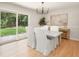 Dining room with modern lighting, white chairs, and sliding glass doors leading to the backyard at 327 Mcclain St, Charleston, SC 29407