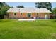 Green lawn, complemented by the rear exterior of the brick home and an inviting patio at 327 Mcclain St, Charleston, SC 29407